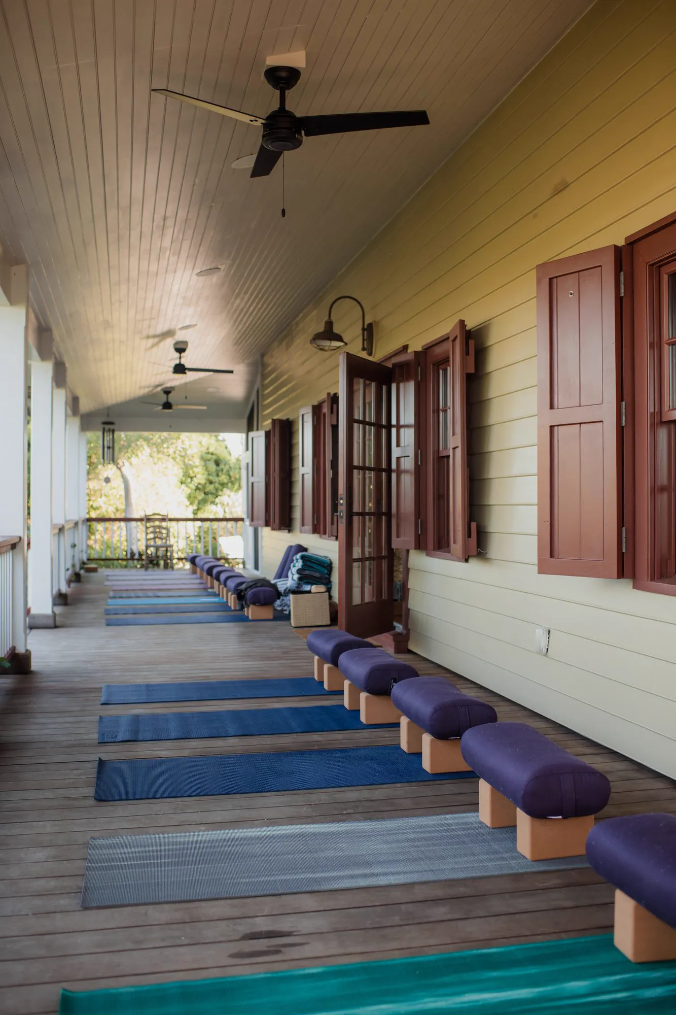 A covered veranda lined with yoga mats, set for morning practice.