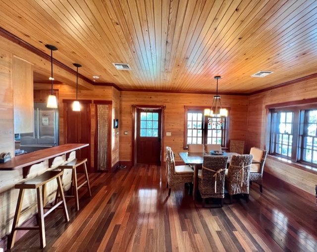 The dining area with a wicker-chair table and breakfast bar with stools beside a Dutch door.