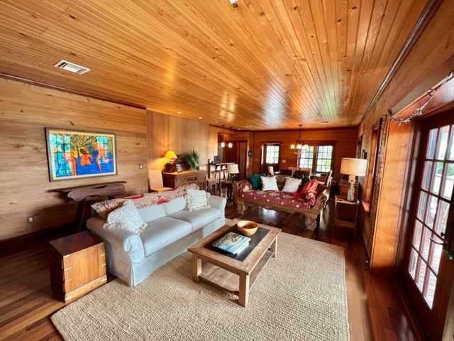 The great room with a white slipcover sofa under a folk-art painting, dining table visible beyond.