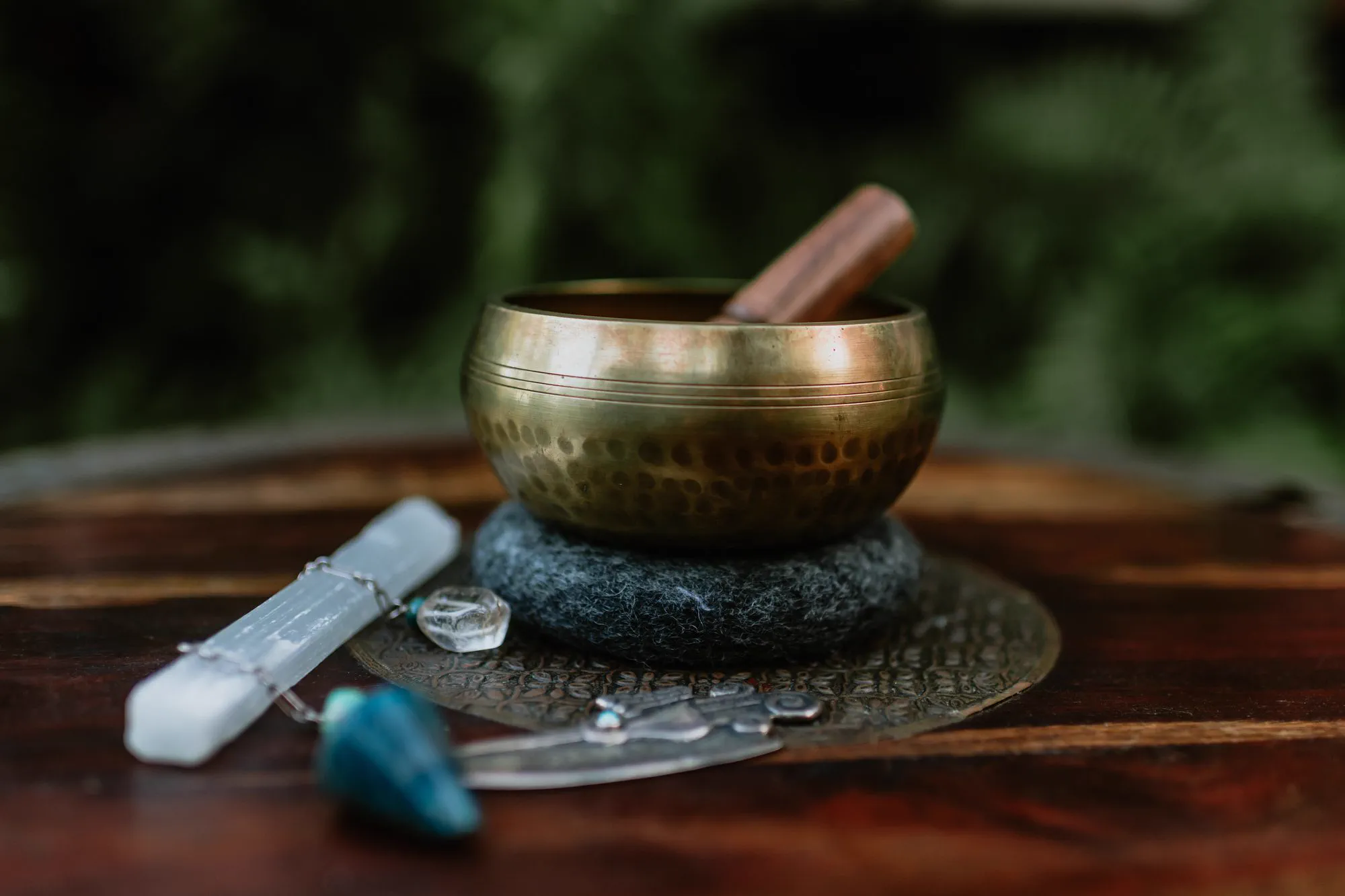 A singing bowl, selenite and crystals arranged in the garden for a sound session.